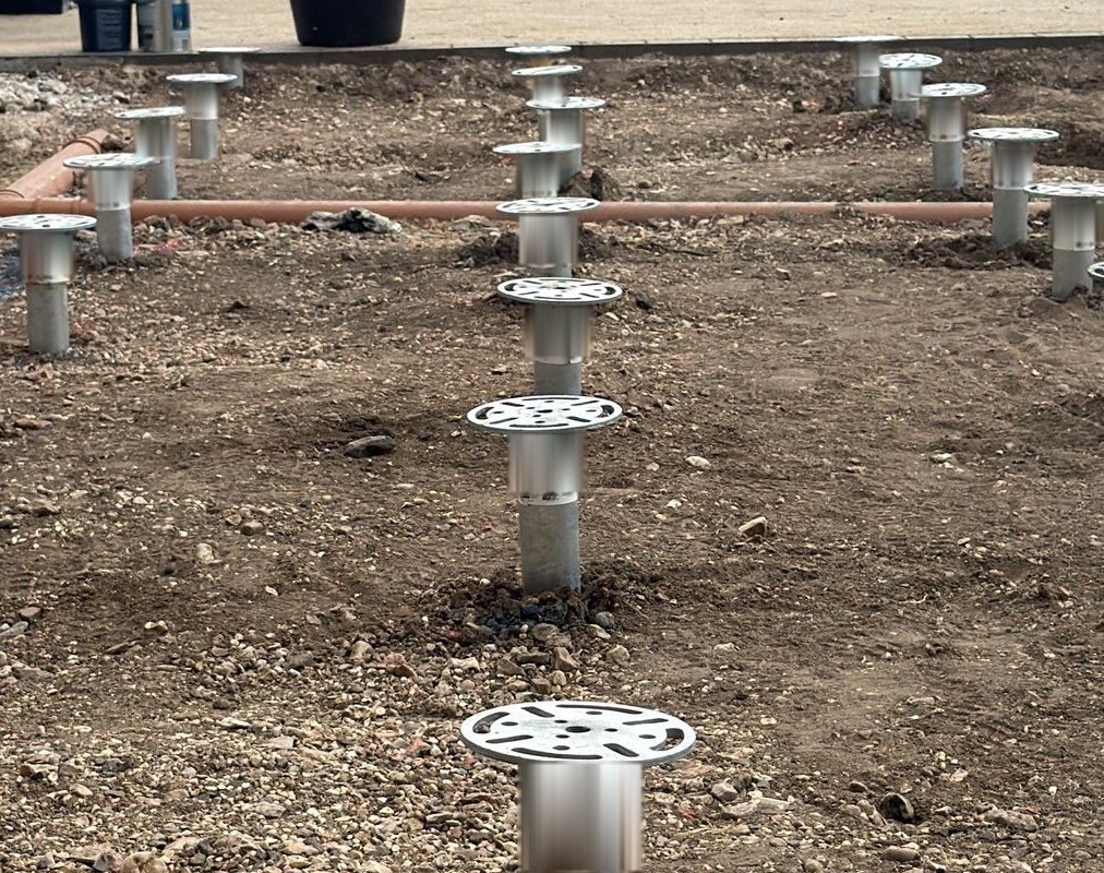 Galvanised ground screws set out in a grid on site